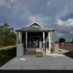 Front entrance of completed community hall with white columns and glass doors