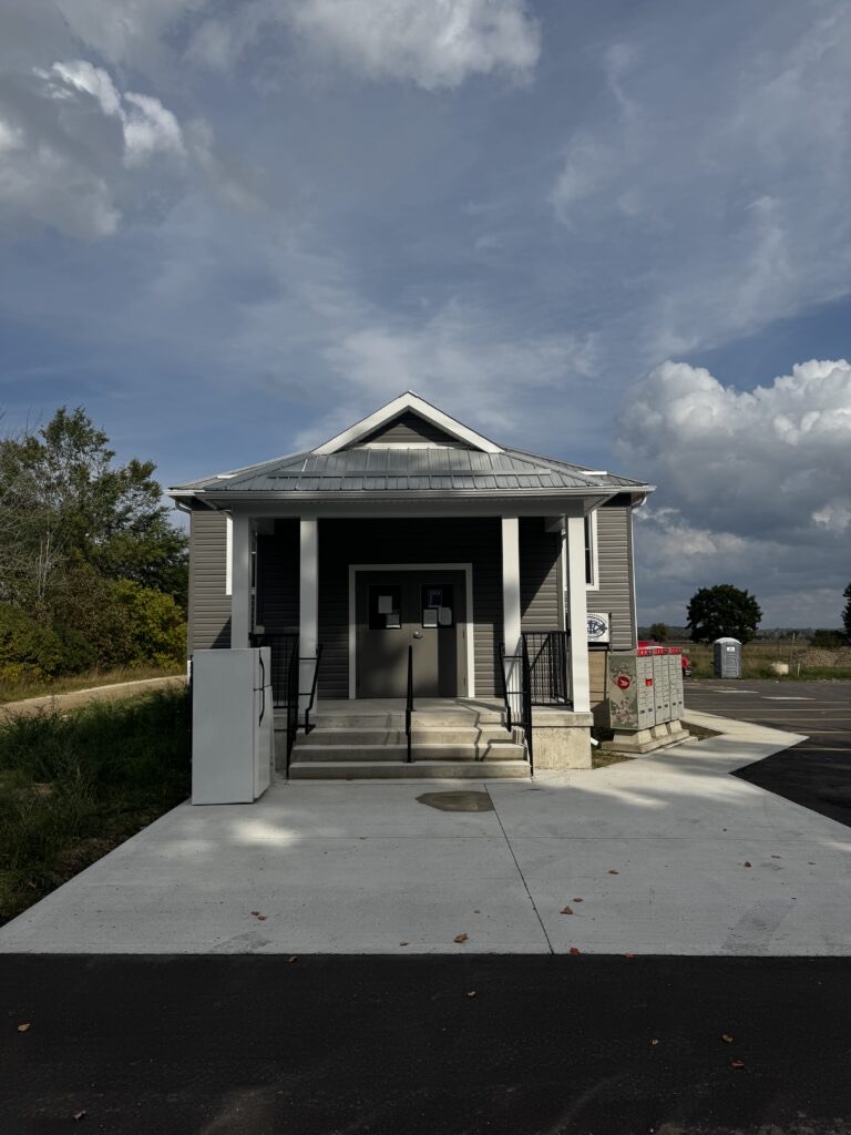 Front entrance of completed community hall with white columns and glass doors