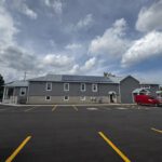 Full exterior view of community hall with parking lot and fresh asphalt