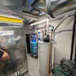 Mechanical room showing installed hot water tank and plumbing connections