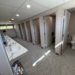 Completed multi-station washroom with marble-look sink counters and stalls