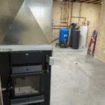 Finished basement mechanical room with blue pressure tank and organized brass piping manifold