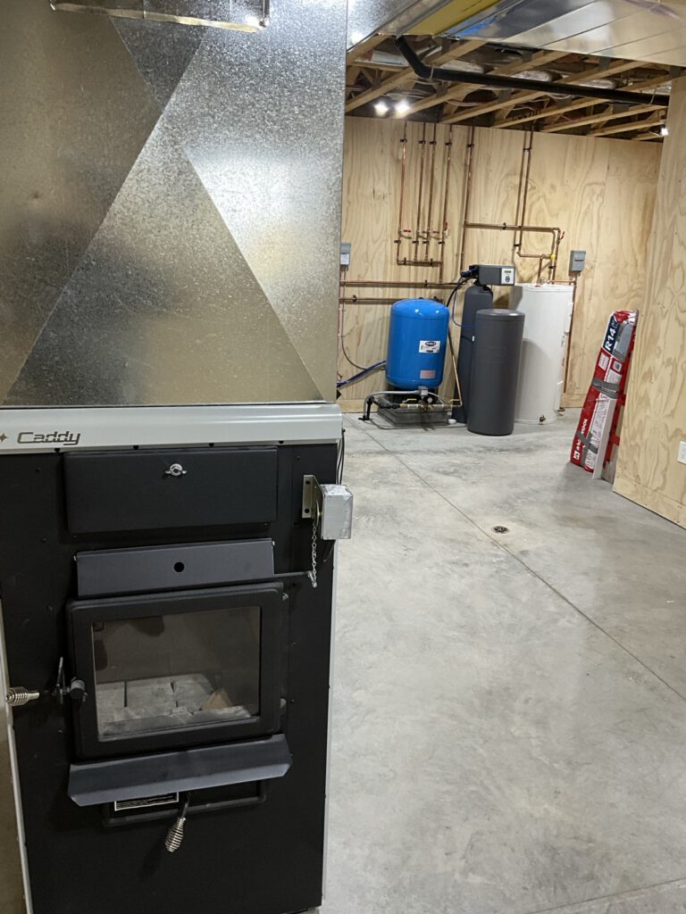 Finished basement mechanical room with blue pressure tank and organized brass piping manifold
