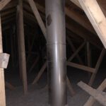 Metal exhaust vent pipe with 90-degree elbows installed in attic space