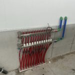 In-floor manifold system with red and white valve tubing arranged on concrete surface