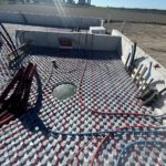 Wide view of installed outdoor radiant heating system with farm buildings and fields in background