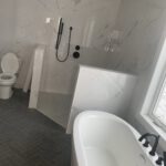 Marble bathroom with freestanding tub, white vanity, skylight, heated towel rack
