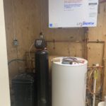 Mechanical room showing water heater, manifold piping with copper lines and controls