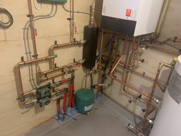 Complete boiler room with dual wall-mounted boilers and extensive copper piping system
