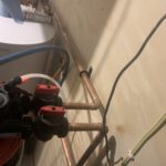 Ceiling-mounted manifold detail showing copper piping with isolation valve handles