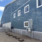 Exterior view of blue metal shed with roof vents and windows