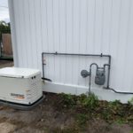 Generac standby generator with manifold piping and gas meter on building