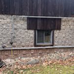 Generac unit installed against stone foundation with electrical conduit and yellow fuel line