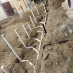 Installed PVC and drain piping on concrete foundation wall