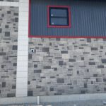 Exterior wall detail showing stone block pattern with red metal trim accent
