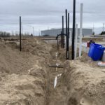 Underground piping installation with excavation and black distribution lines laid in trench