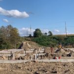 Construction site with foundation pilings, excavation, and equipment