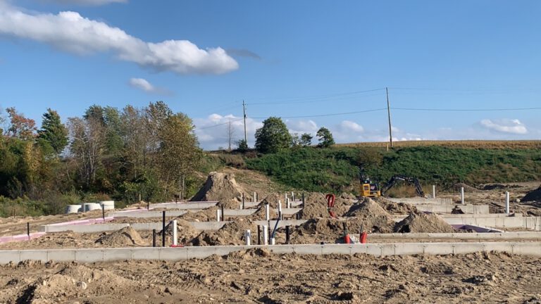 Construction site with foundation pilings, excavation, and equipment