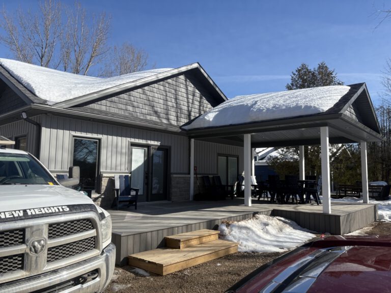Modern cottage exterior with covered deck and snow-covered roof