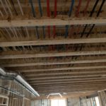 Overhead view of color-coded piping runs through frame cavity