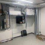 Mechanical room with dual HVAC units, electrical panel, and ductwork