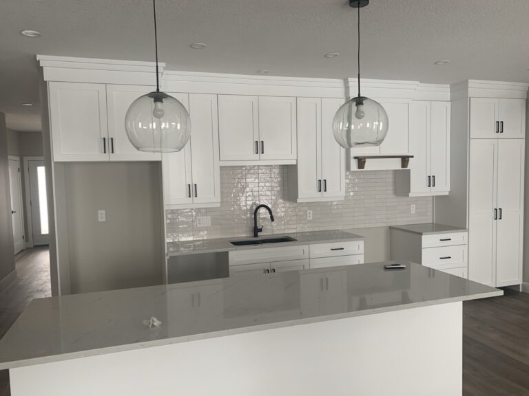 Finished white kitchen with pendant lights and quartz island