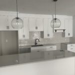 Modern kitchen with white cabinetry, gray quartz countertops, and pendant lights