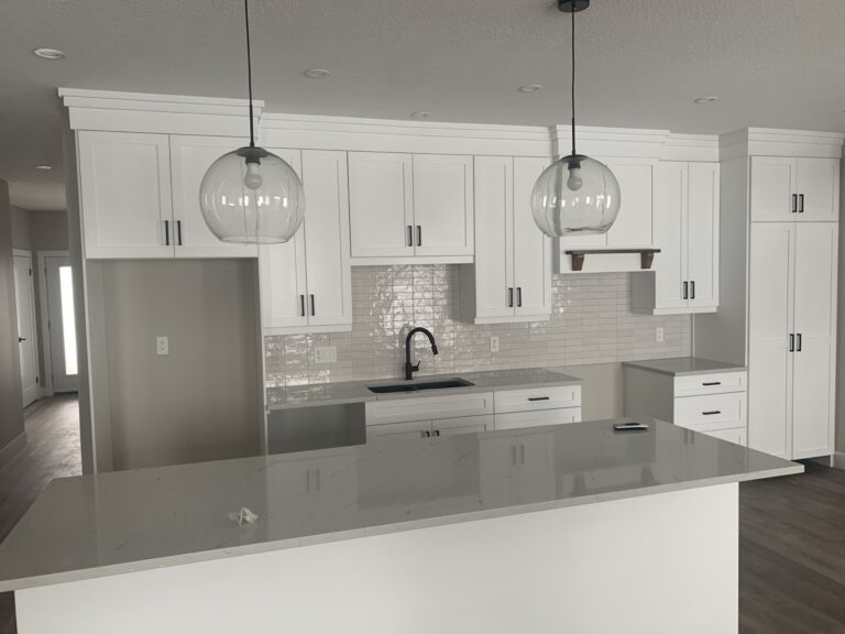 Modern kitchen with white cabinetry, gray quartz countertops, and pendant lights
