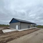Completed pavilion with gray brick walls, blue roof, white columns