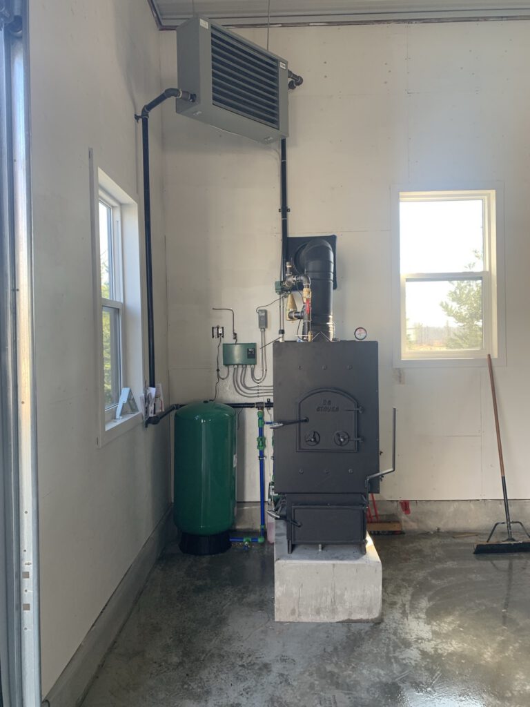 Outdoor wood boiler furnace installed indoors with expansion tank