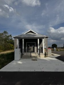 Front entrance of completed community hall with white columns and glass doors