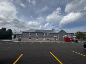 Full exterior view of community hall with parking lot and fresh asphalt