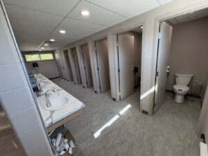 Completed multi-station washroom with marble-look sink counters and stalls