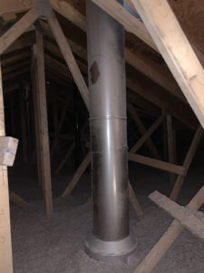 Metal exhaust vent pipe with 90-degree elbows installed in attic space