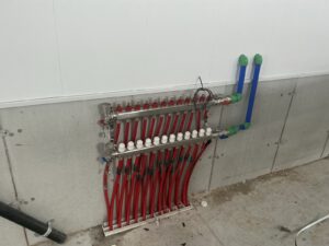 In-floor manifold system with red and white valve tubing arranged on concrete surface