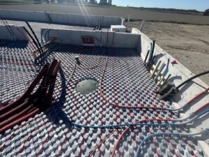 Wide view of installed outdoor radiant heating system with farm buildings and fields in background
