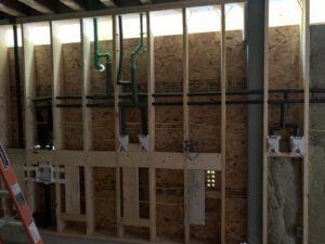 Organized commercial pipe rough-in on framed wall with ladder