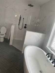 Marble bathroom with freestanding tub, white vanity, skylight, heated towel rack