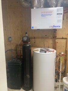Mechanical room showing water heater, manifold piping with copper lines and controls