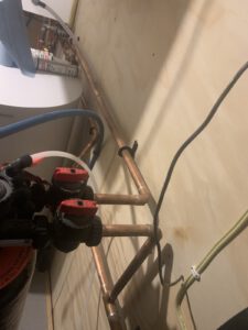 Ceiling-mounted manifold detail showing copper piping with isolation valve handles