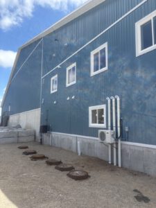 Exterior view of blue metal shed with roof vents and windows