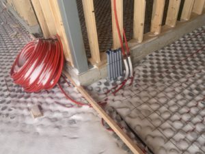 In-floor radiant heating system with coiled red PEX tubing on foundation