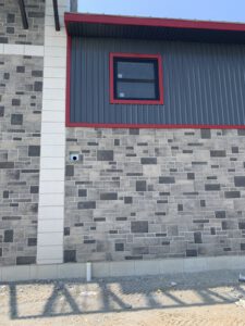 Exterior wall detail showing stone block pattern with red metal trim accent