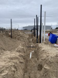 Underground piping installation with excavation and black distribution lines laid in trench