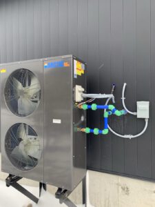 Outdoor heat pump unit with manifold piping and color-coded fittings