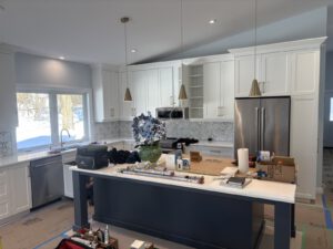 Modern kitchen with white cabinets, dark island, stainless appliances
