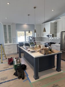 Kitchen in progress showing white cabinetry and marble backsplash