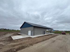 Completed pavilion with gray brick walls, blue roof, white columns